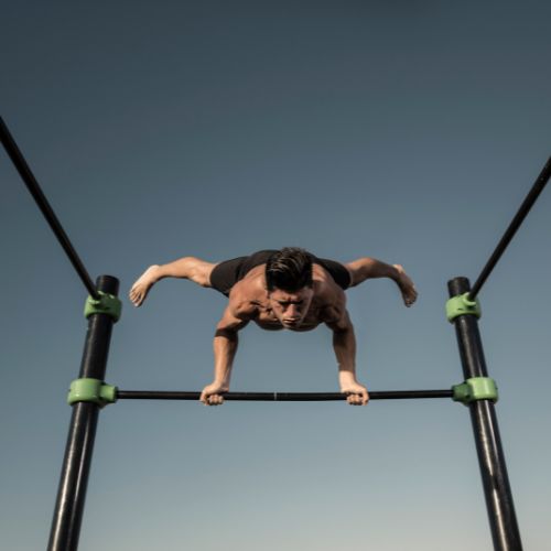 Un hombre elevado hacia arriba en una barra de calistenia