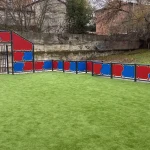 Pista multideporte instalada con paneles rojos y azules, canastas y porterías y con césped artificial