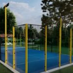 Fotografía de una pista de pádel con barrotes amarillos y cristal