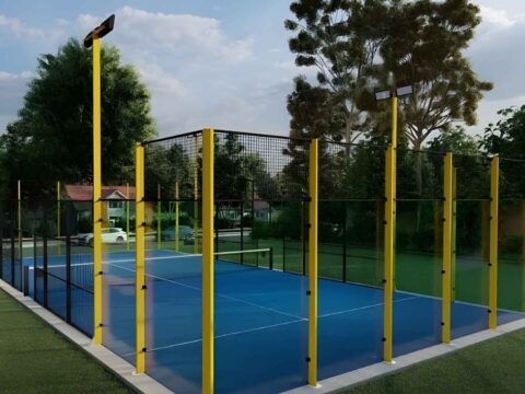 Fotografía de una pista de pádel con barrotes amarillos y cristal