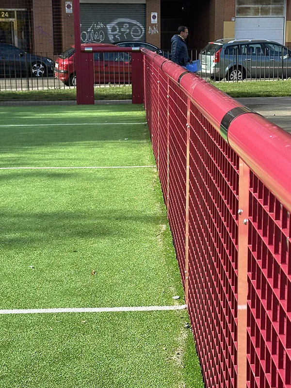 Primer plano de una barandilla roja de una pista multideporte