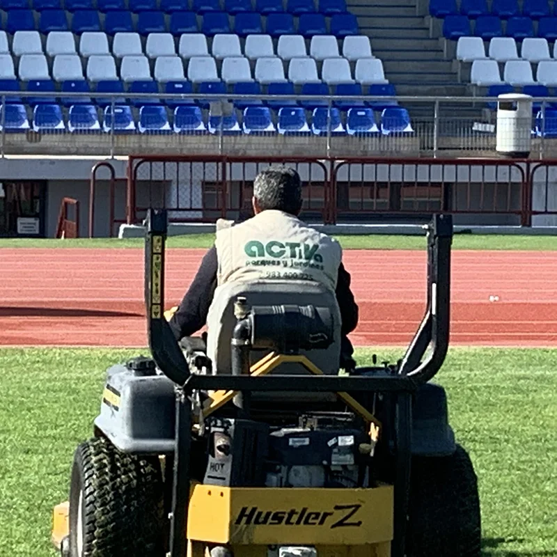 Personal de Activa utilizando maquinaria para el mantenimiento de un campo de fútbol con césped natural deportivo