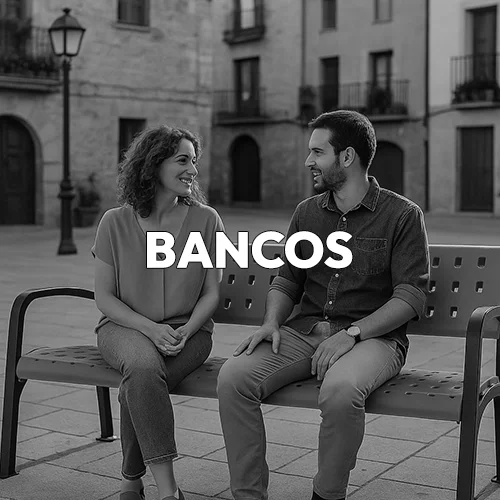 Una pareja sentada en uno de nuestros bancos en la plaza de un pueblo en blanco y negro