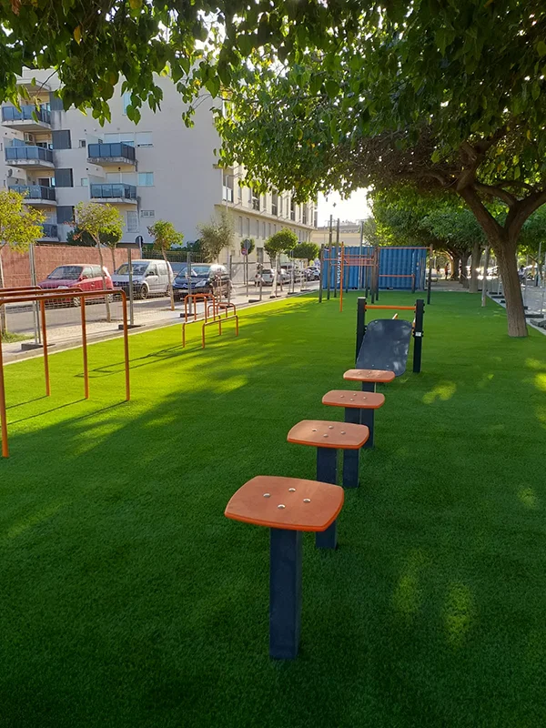 Elementos de un área de calistenia con césped artificial debajo