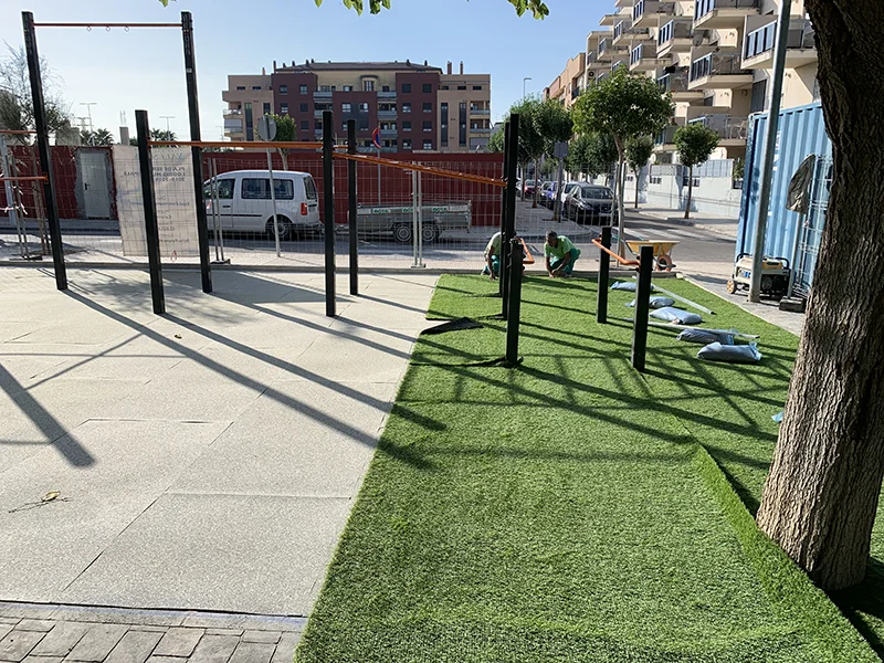 Operarios instalando césped artificial en un área de calistenia recién instalada