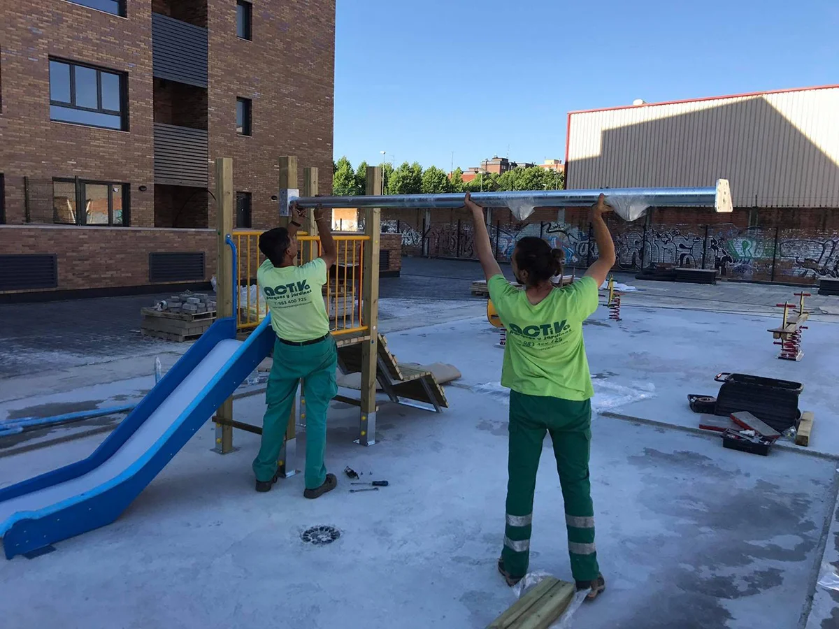 Dos personas de Activa Sport instalando un parque infantil